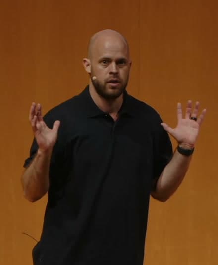 Mike Skinner speaking to a room, hands open